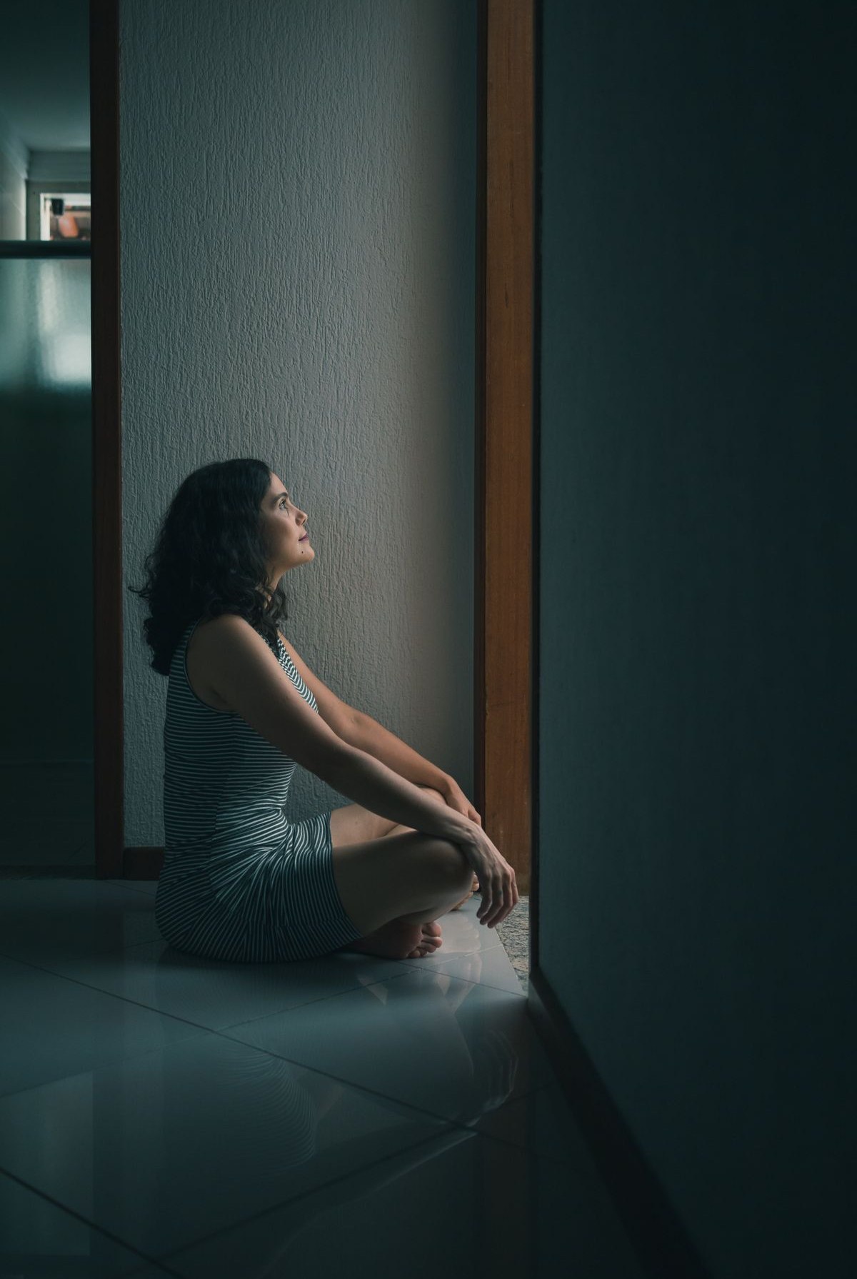 A person sitting alone indoors in thought, representing the decision and adjustment that separation and divorce therapy supports