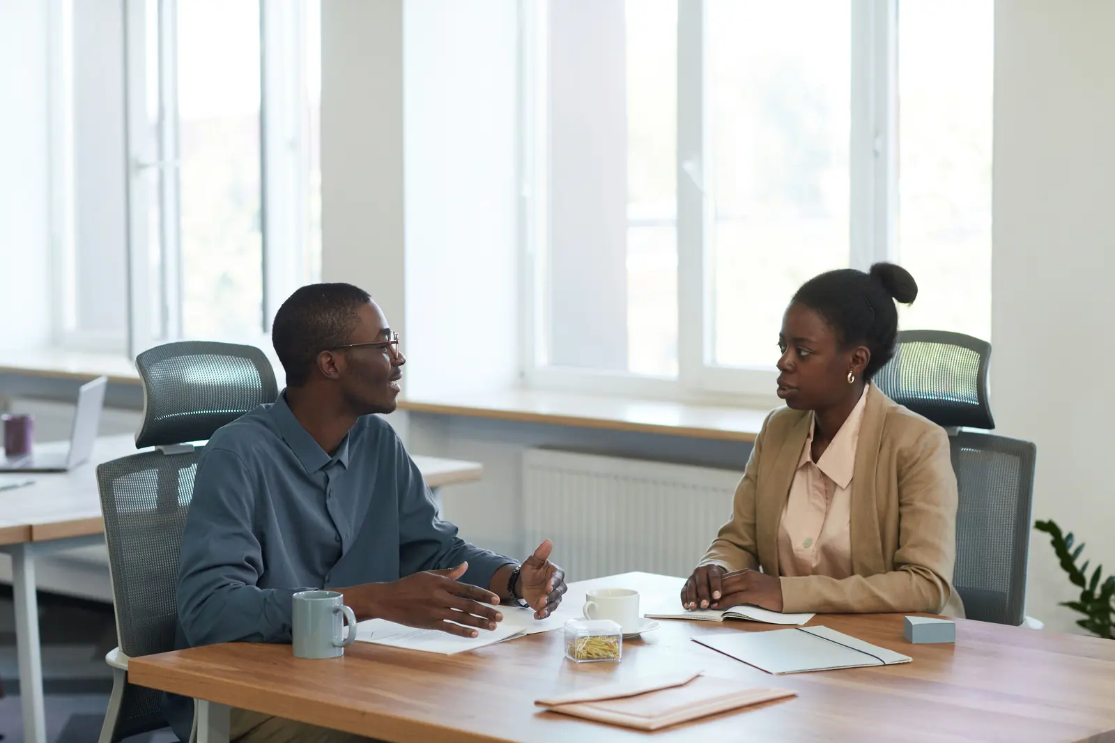 Two colleagues talking across a table in warm daylight