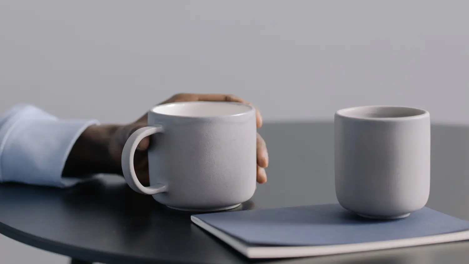 Two mugs of tea on a table between two people talking