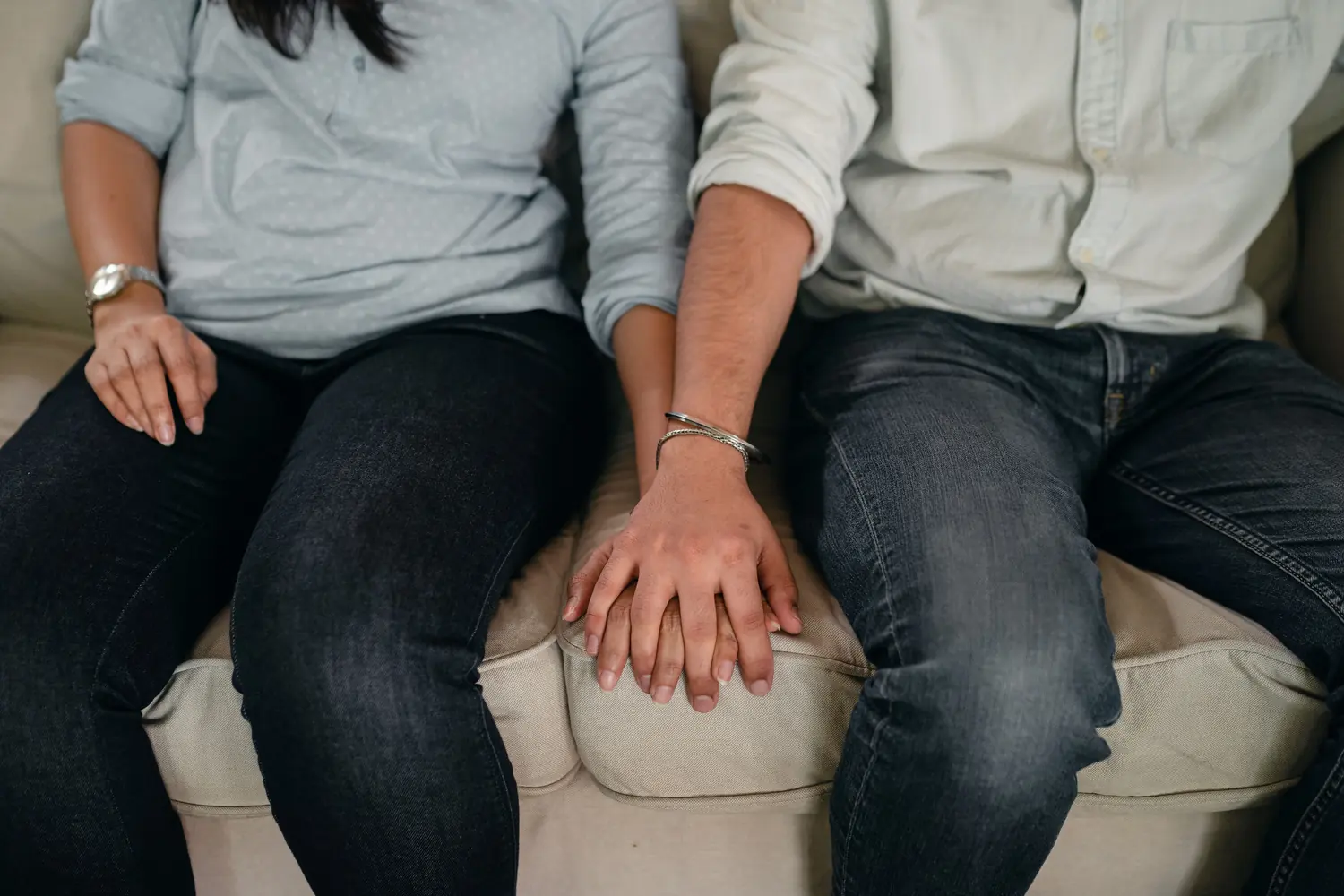 A couple sitting close together, hands joined