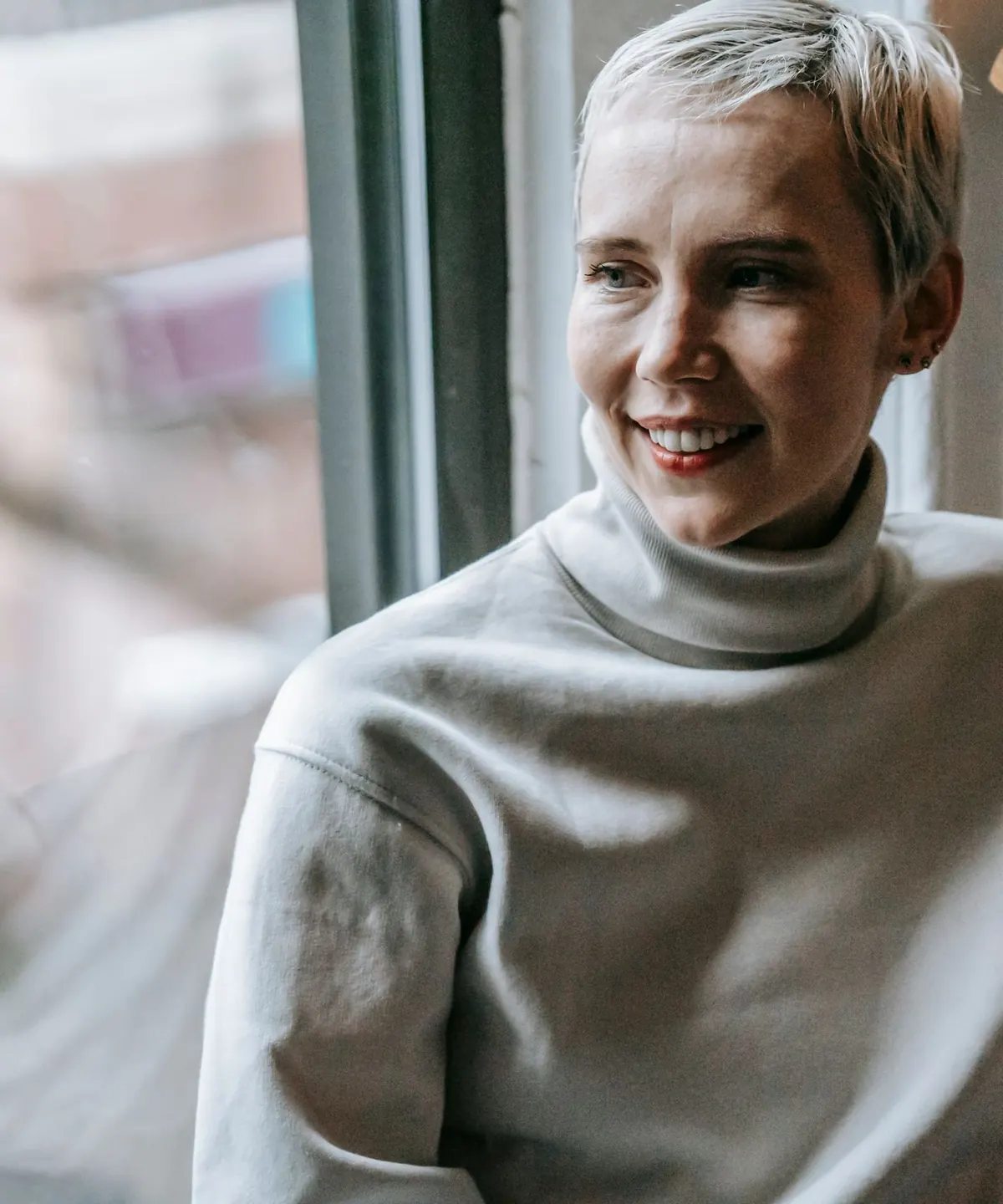 A woman smiling by a window in natural light