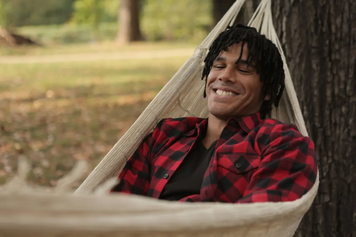 A man smiles as he relaxes in a hammock outdoors