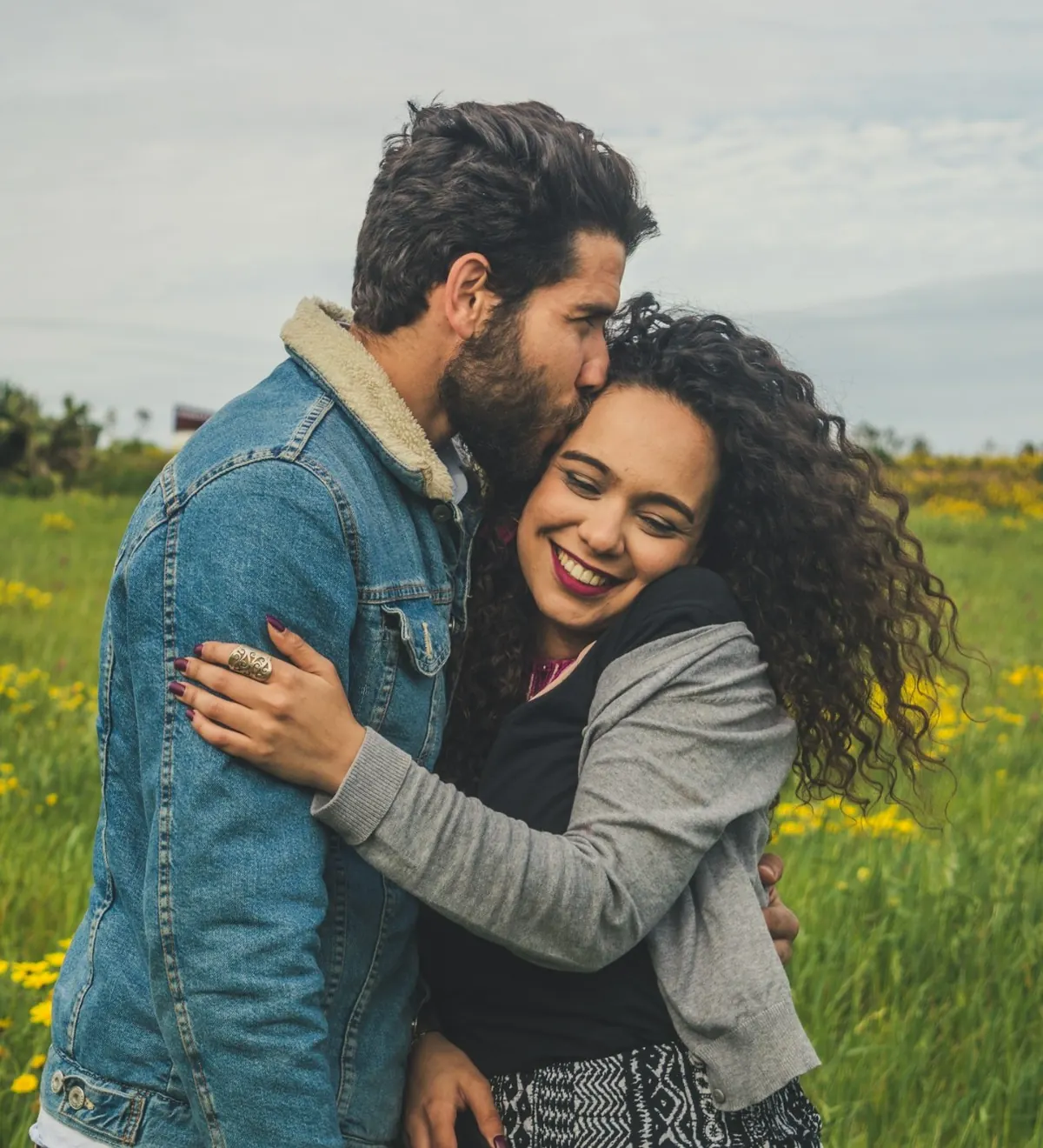A couple embracing in a meadow of yellow flowers, smiling